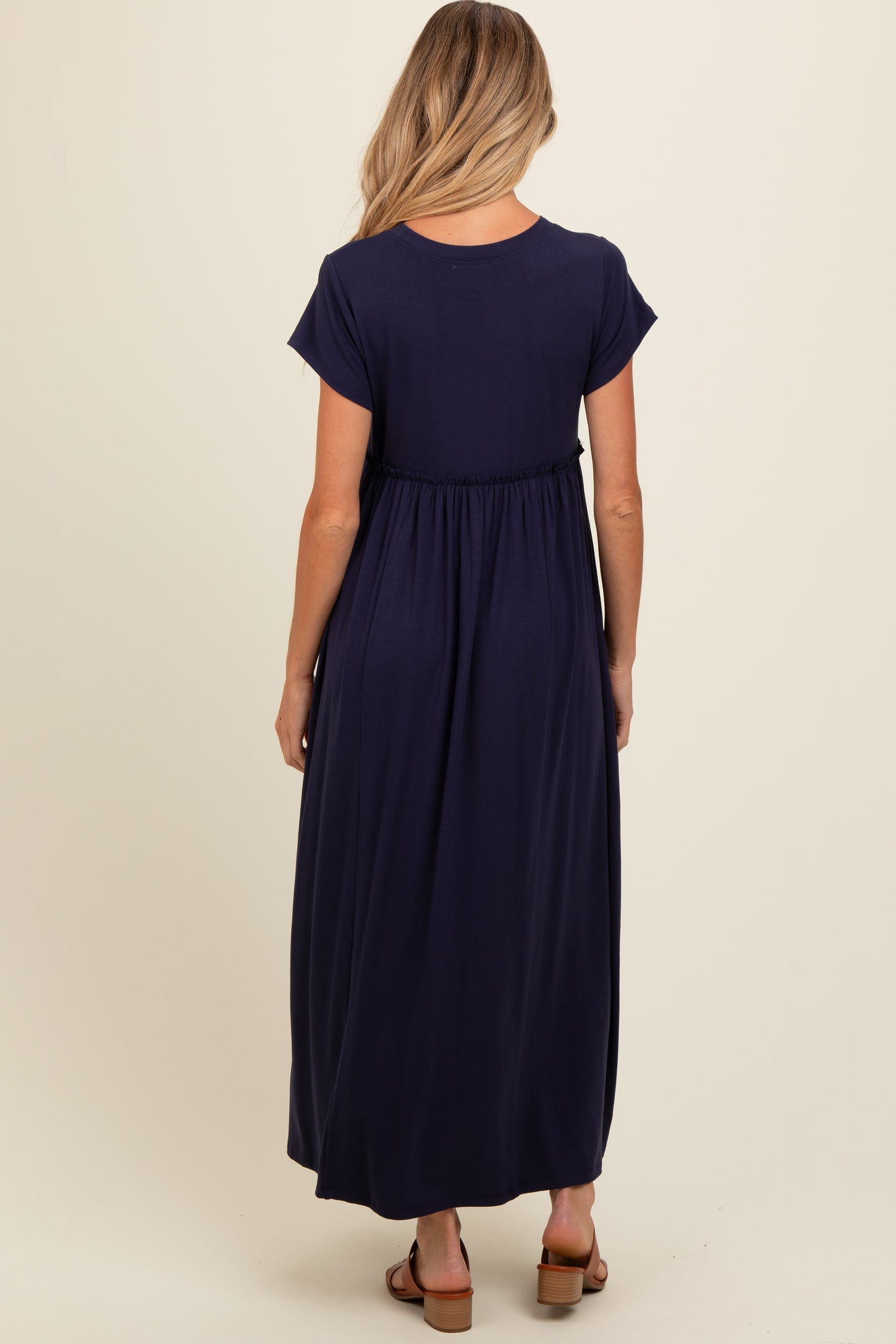 woman wearing a navy blue maternity maxi dress with short sleeves and a cinched waist, showing her baby bump