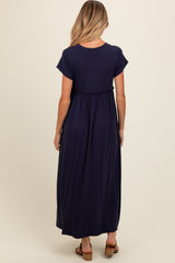woman wearing a navy blue maternity maxi dress with short sleeves and a cinched waist, showing her baby bump