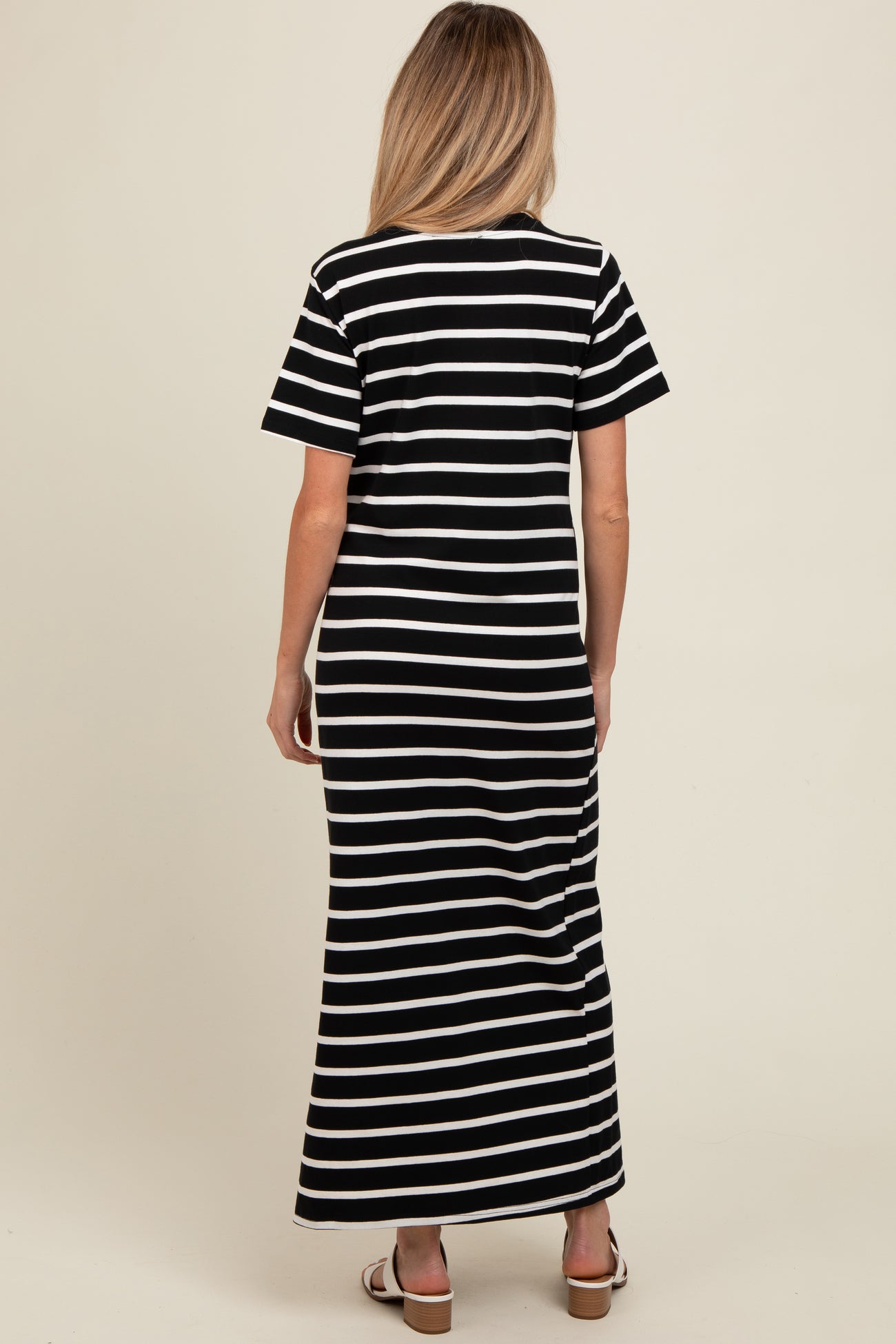woman wearing a black and white striped maternity maxi dress, shown from the back