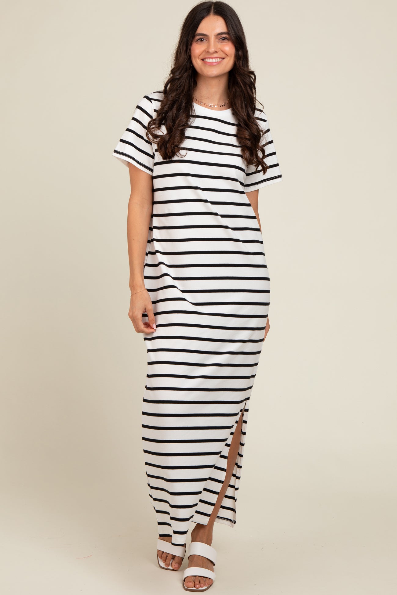 woman wearing a white and black striped maxi dress with short sleeves and a side slit