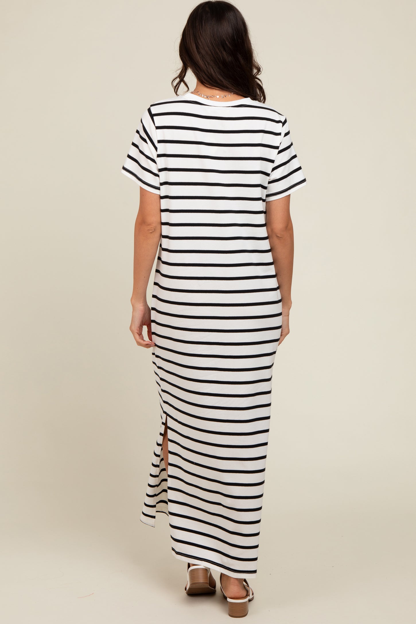 woman wearing a white and black striped maxi dress with short sleeves and side slits