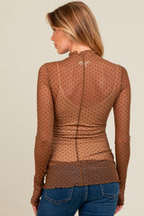 woman wearing a brown sheer maternity top with black polka dots and long sleeves, styled with a ruffled collar