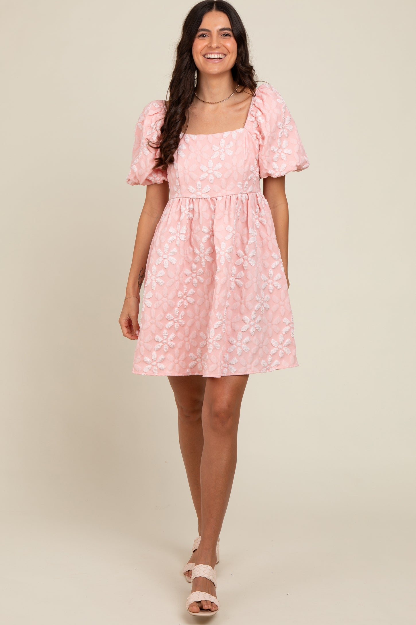 woman wearing a pink floral puff sleeve dress with a square neckline and a fitted waist