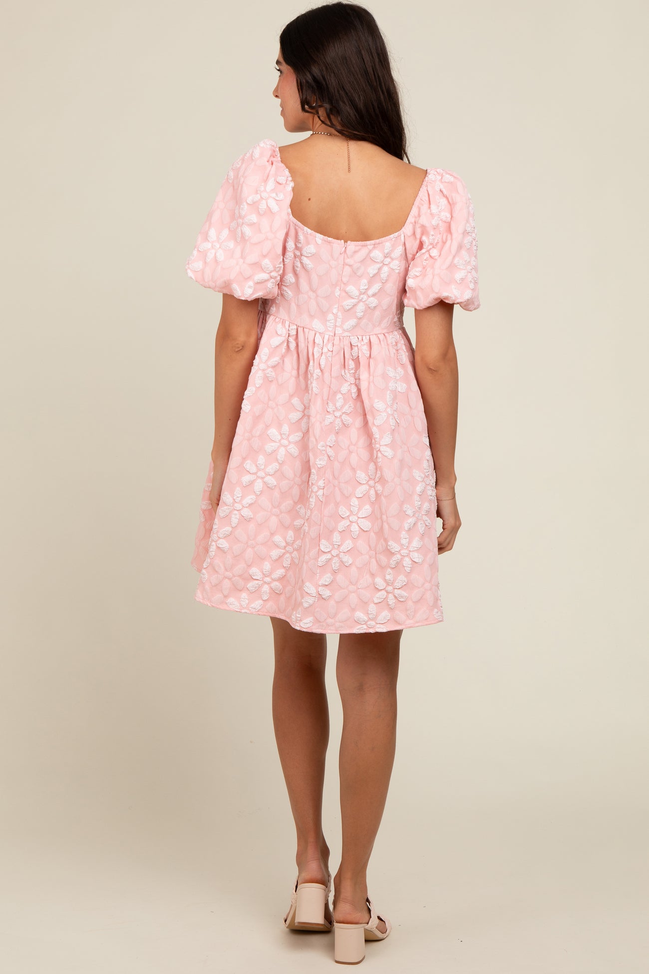 woman wearing a pink puff sleeve dress with floral embroidery, showing the back view