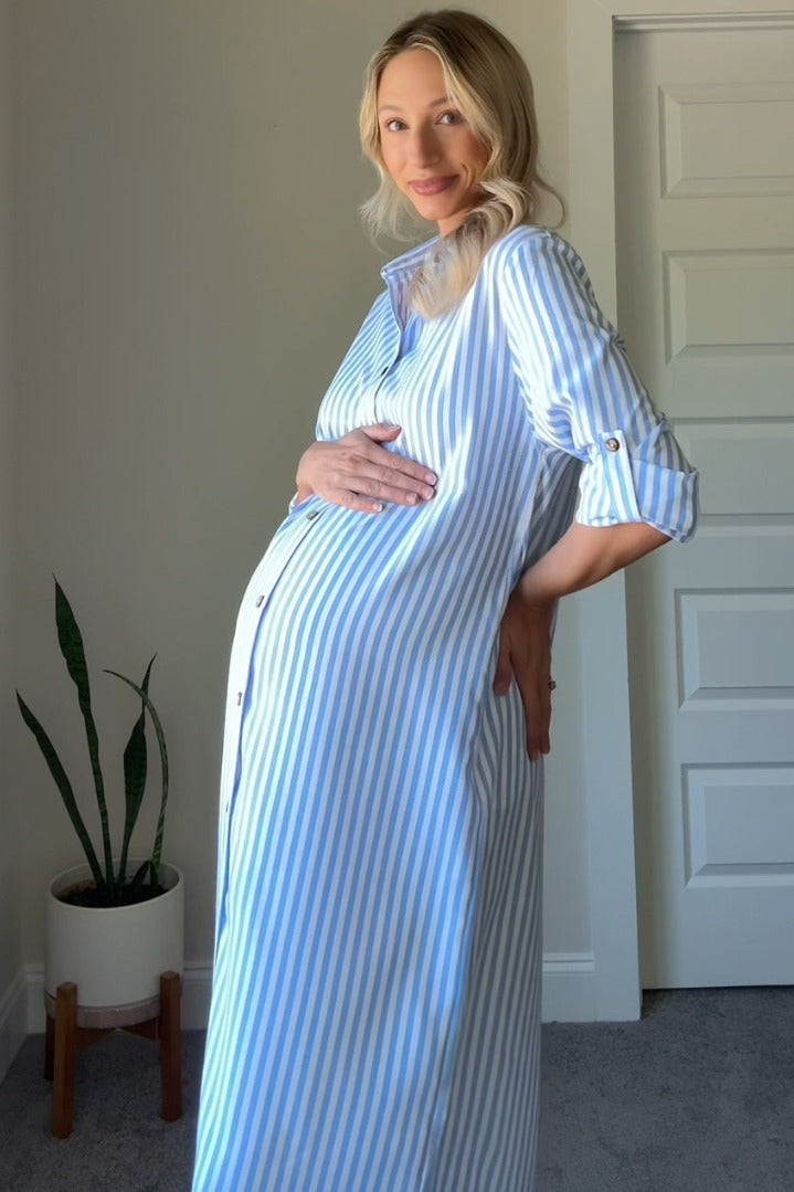 woman wearing a striped blue and white maternity dress, gently cradling her baby bump