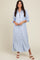 woman wearing a blue and white striped long button-up dress with rolled sleeves and a side slit