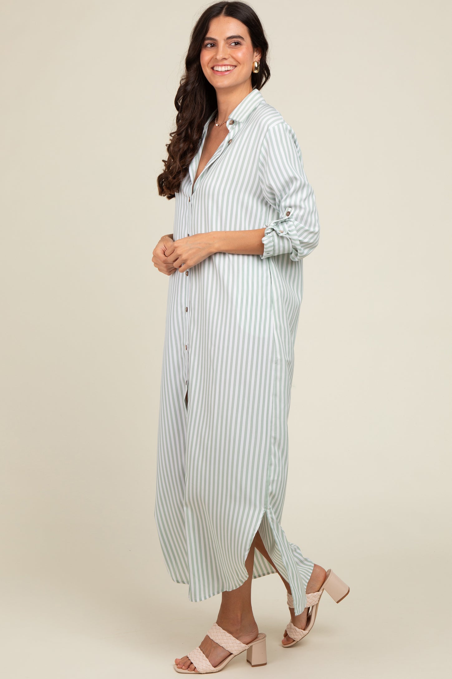 woman wearing a long striped button-up dress in light blue and white, paired with blush pink block-heeled sandals