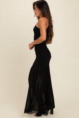 woman wearing a black strapless maxi dress with ruched detailing and a flowing skirt, shown from the side