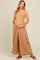 woman wearing a floral print brown maternity maxi dress, holding her baby bump.