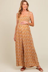 woman wearing a floral print maternity jumpsuit with a fitted bodice and wide leg, cradling her baby bump