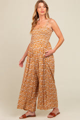 woman wearing a floral patterned maternity jumpsuit with a smocked bodice and wide-leg pants, showcasing her baby bump