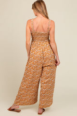 woman wearing a floral maternity jumpsuit with smocked bodice and wide leg pants, showing the back view