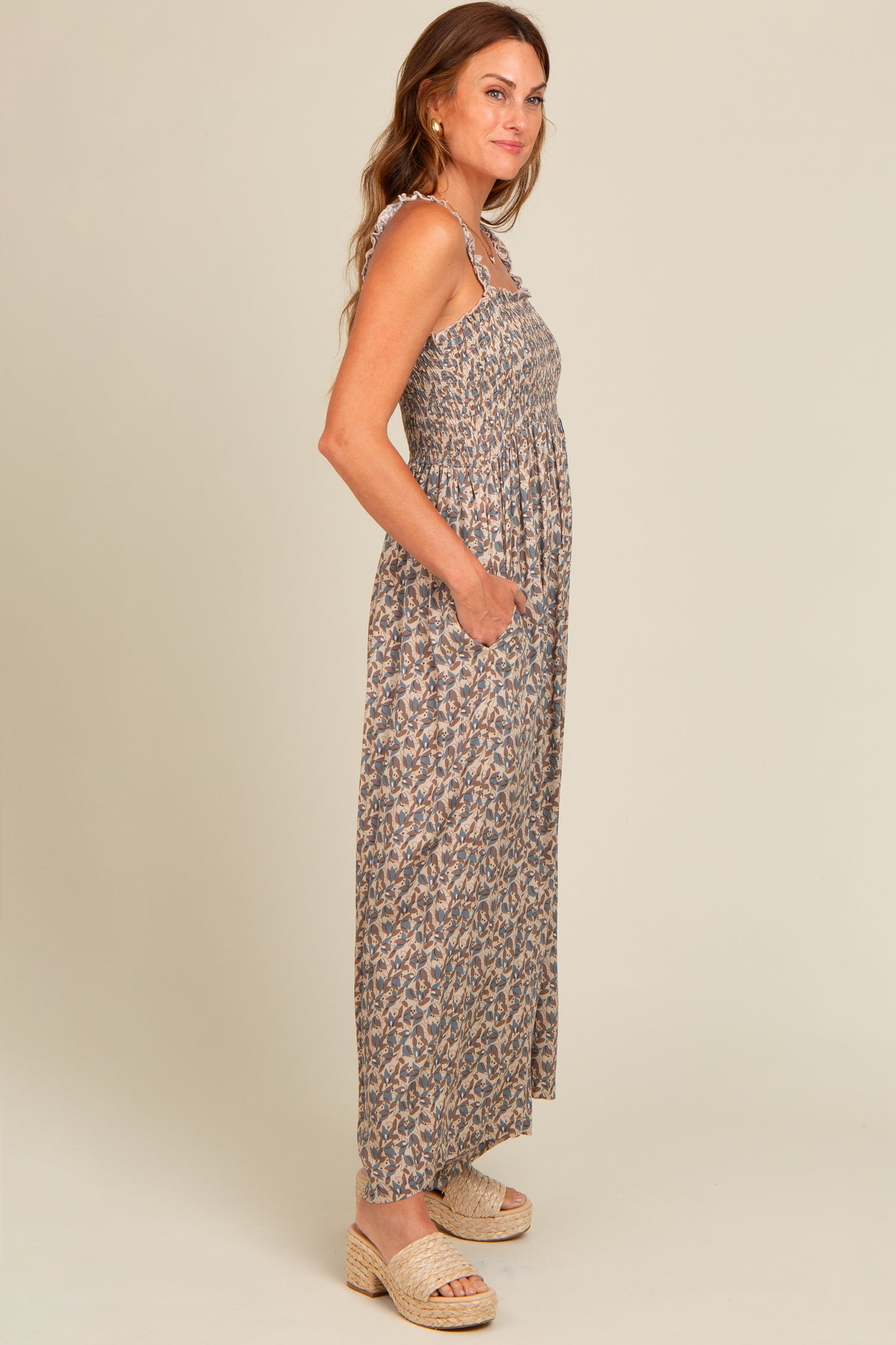woman wearing a long floral print maxi dress with pockets and strappy shoulders