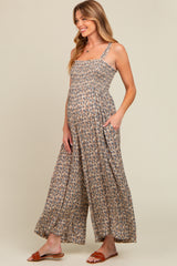 woman wearing a floral patterned maternity jumpsuit with a smocked bodice and wide-leg pants, showing her baby bump