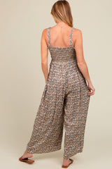 woman wearing a floral print maternity jumpsuit with smocked bodice and wide-leg pants, viewed from the back