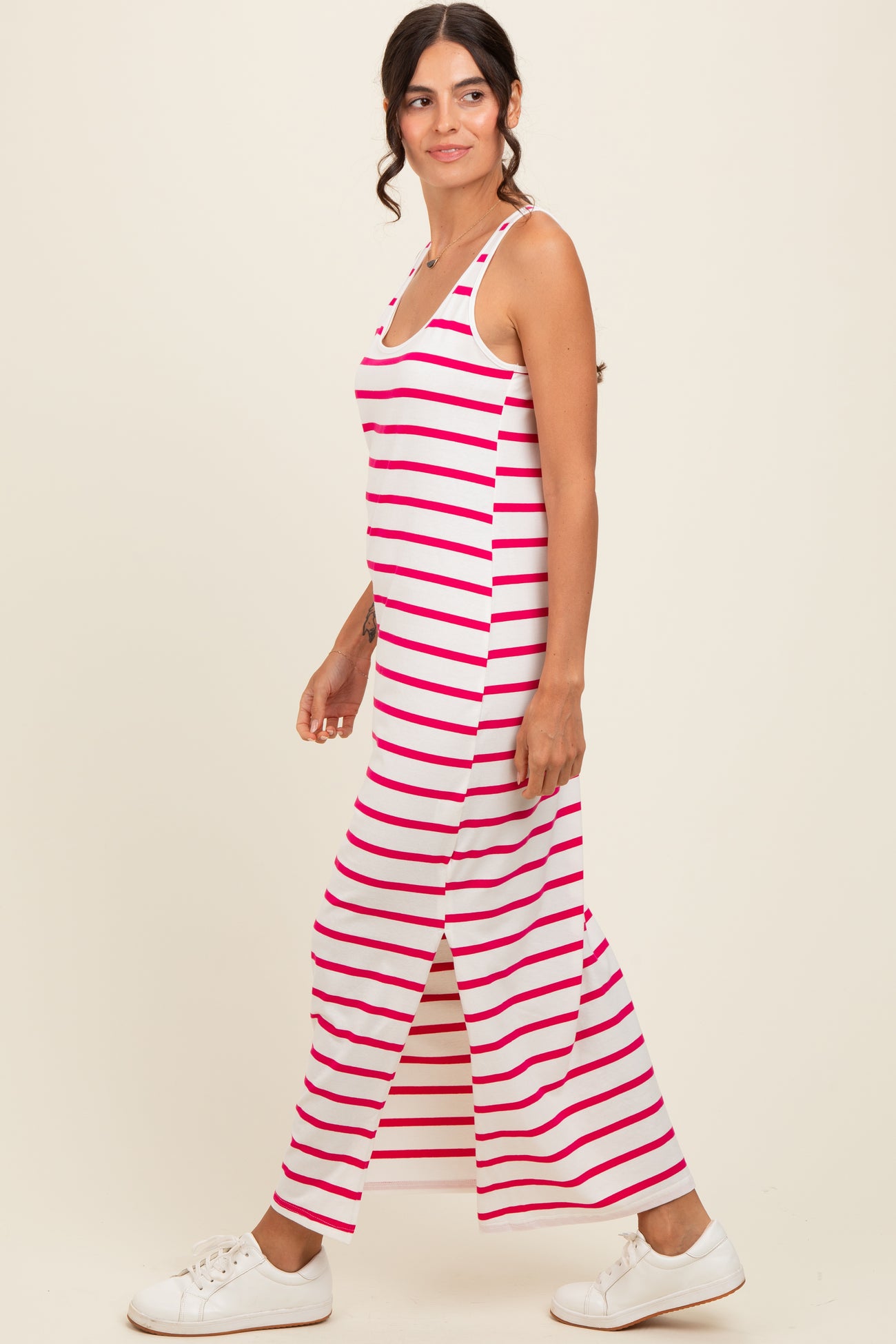 woman wearing a pink and white striped maxi dress with side slits and white sneakers