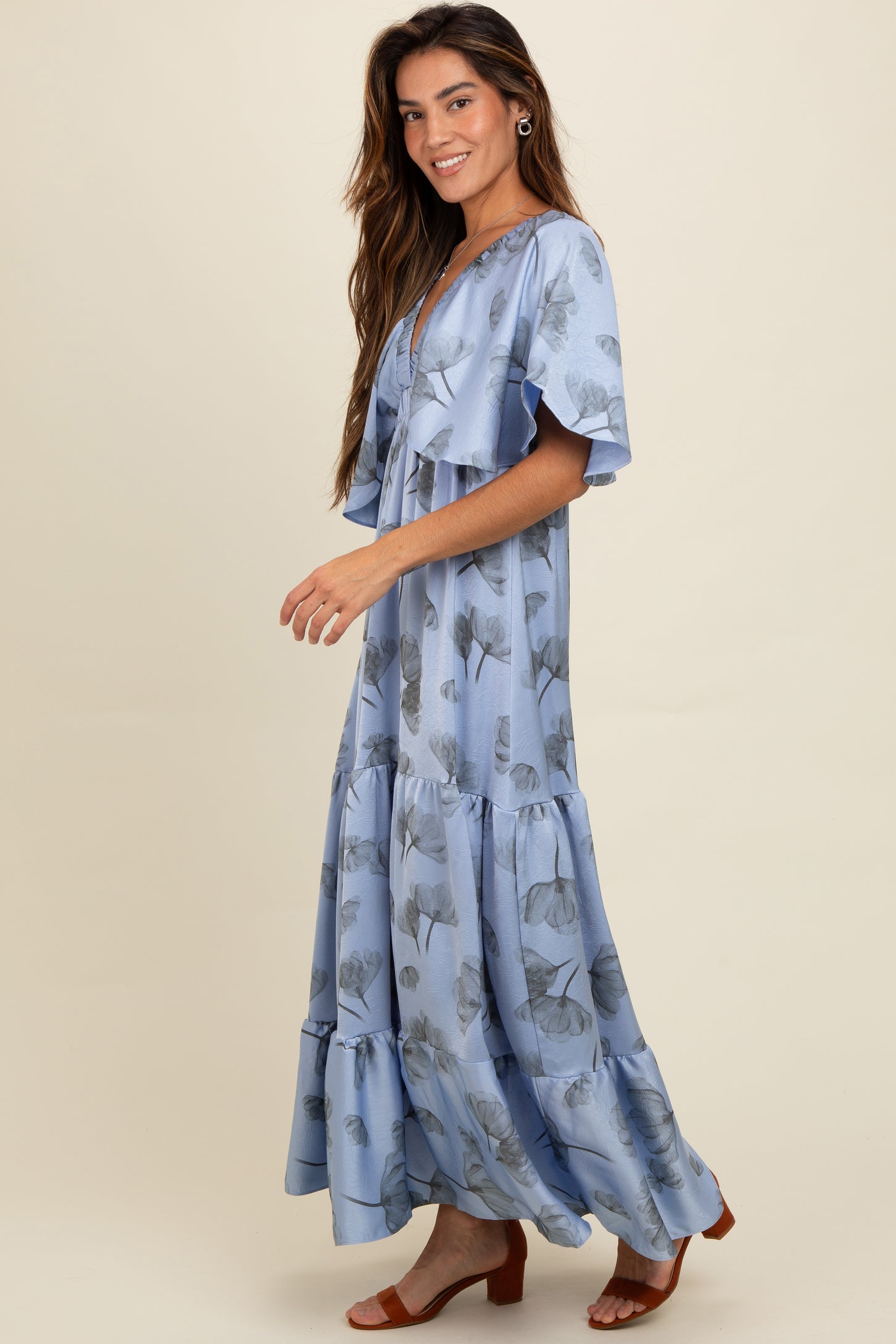 woman wearing a light blue floral maxi dress with ruffles and flowing sleeves
