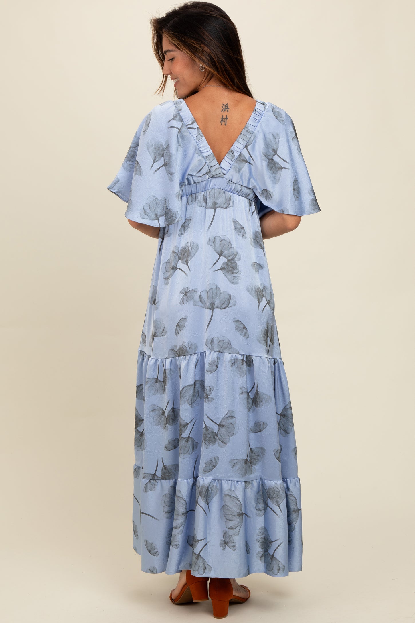 woman wearing a light blue floral print maxi dress with short sleeves and tiered ruffle detail, seen from the back