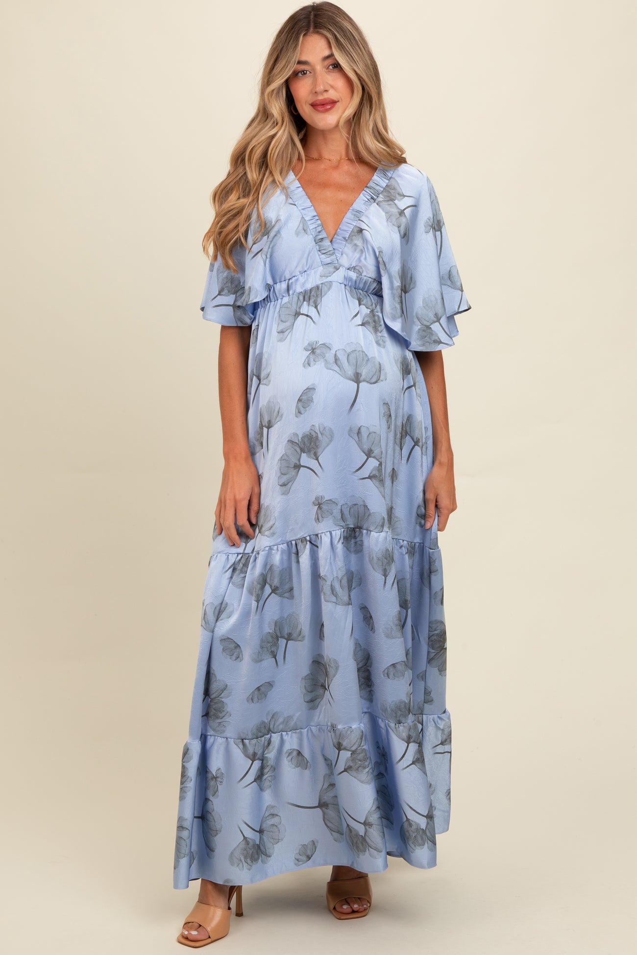 woman wearing a light blue floral maternity maxi dress with flutter sleeves and a visible baby bump