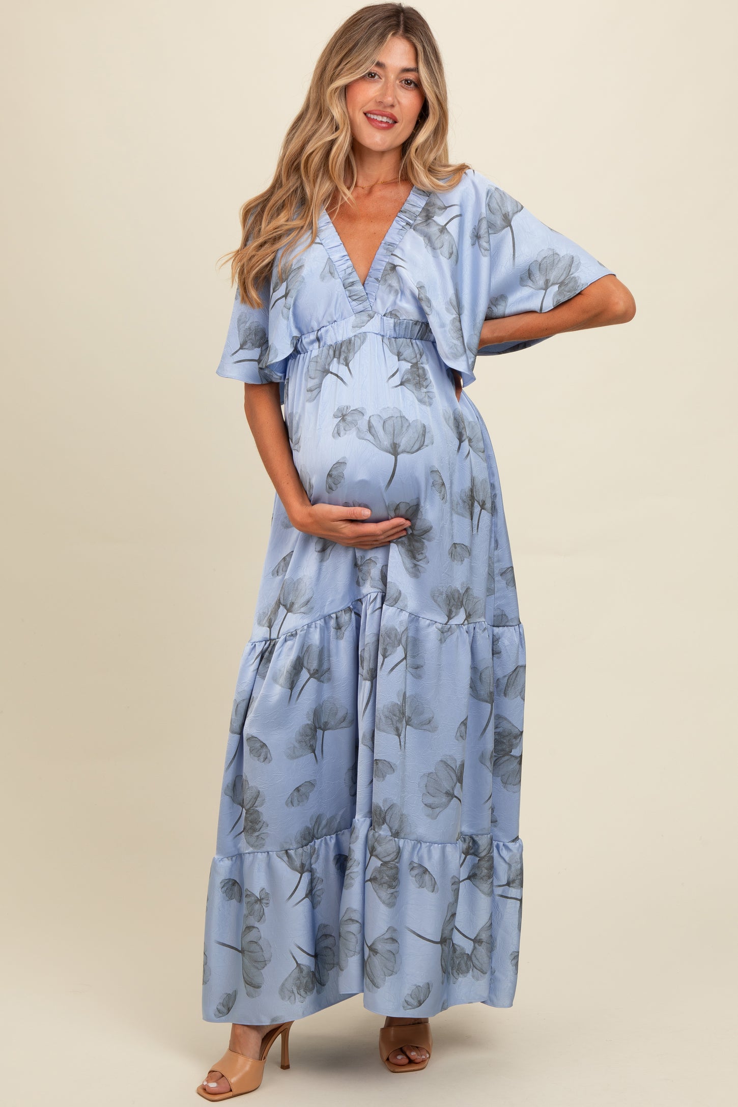 woman wearing a light blue floral print maternity maxi dress and holding her baby bump