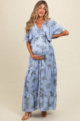 woman wearing a light blue floral print maternity maxi dress and holding her baby bump