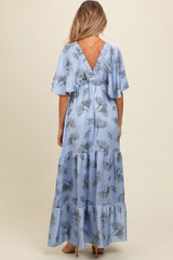 woman wearing a light blue floral maternity maxi dress with flutter sleeves and a V-back style