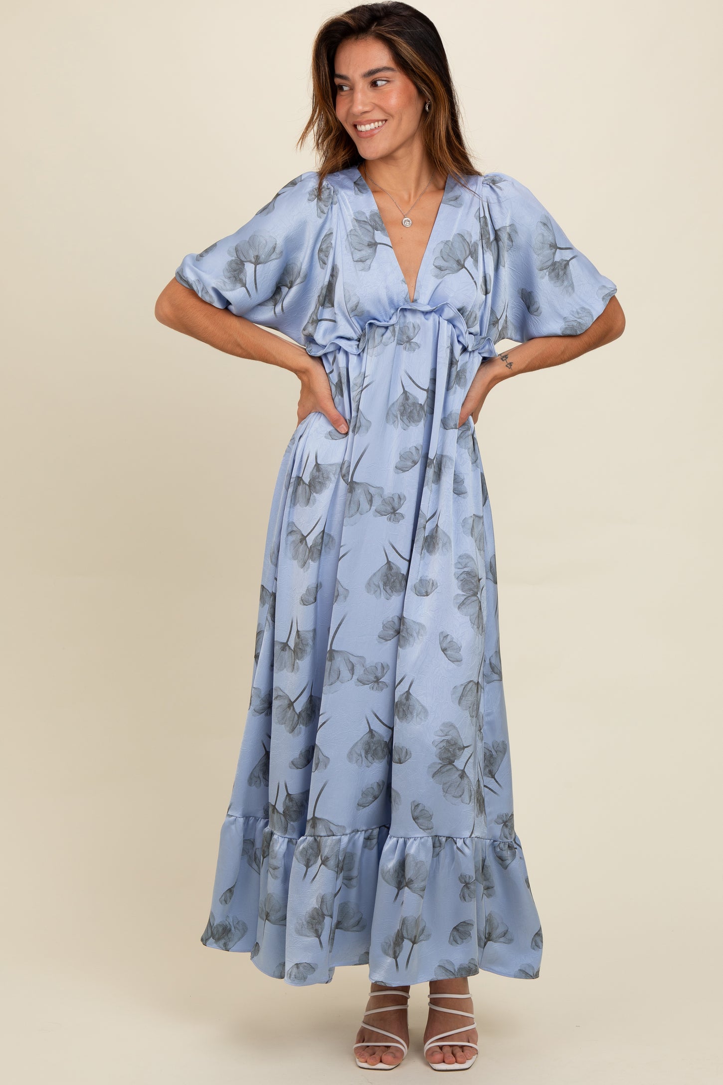 woman wearing a light blue floral maxi dress with wide sleeves and a ruffled hemline