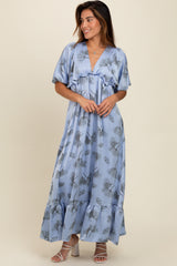 woman wearing a light blue floral maxi dress with short sleeves and a ruffled hem