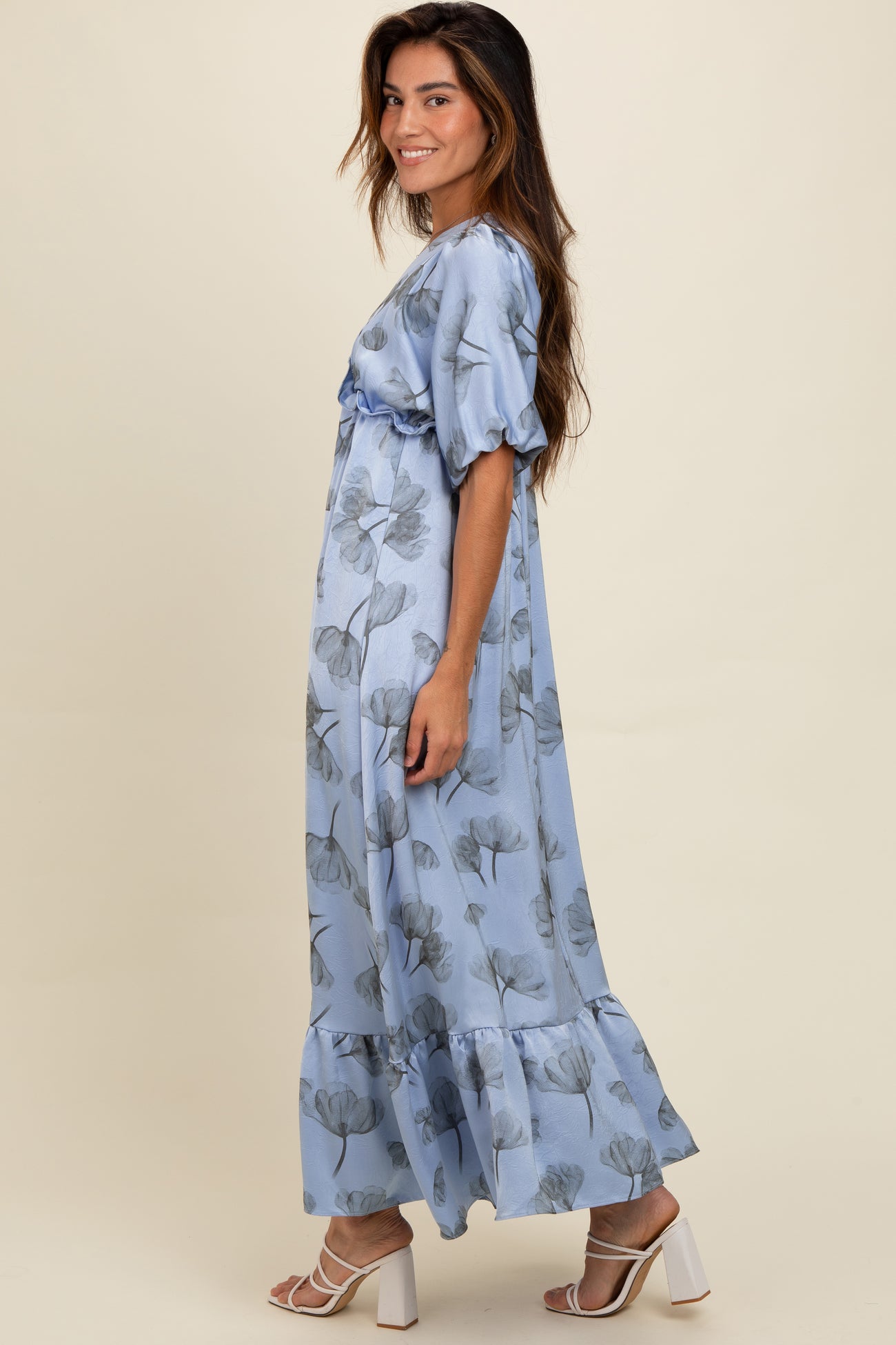 woman wearing a light blue floral maxi dress with puff sleeves and a ruffled hem, posed sideways