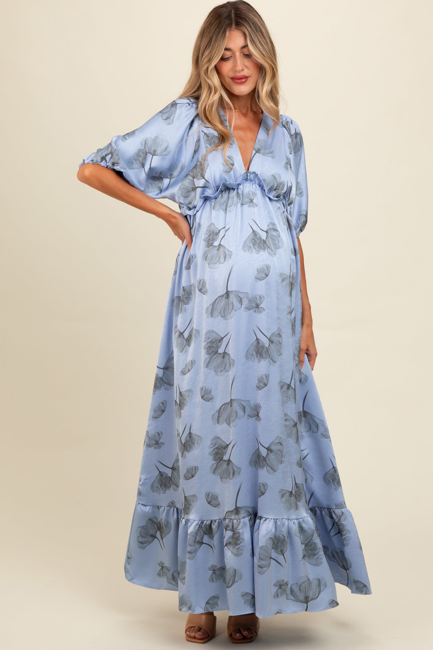 woman wearing a light blue floral maternity maxi dress with a tiered hem and short puff sleeves, showing her baby bump
