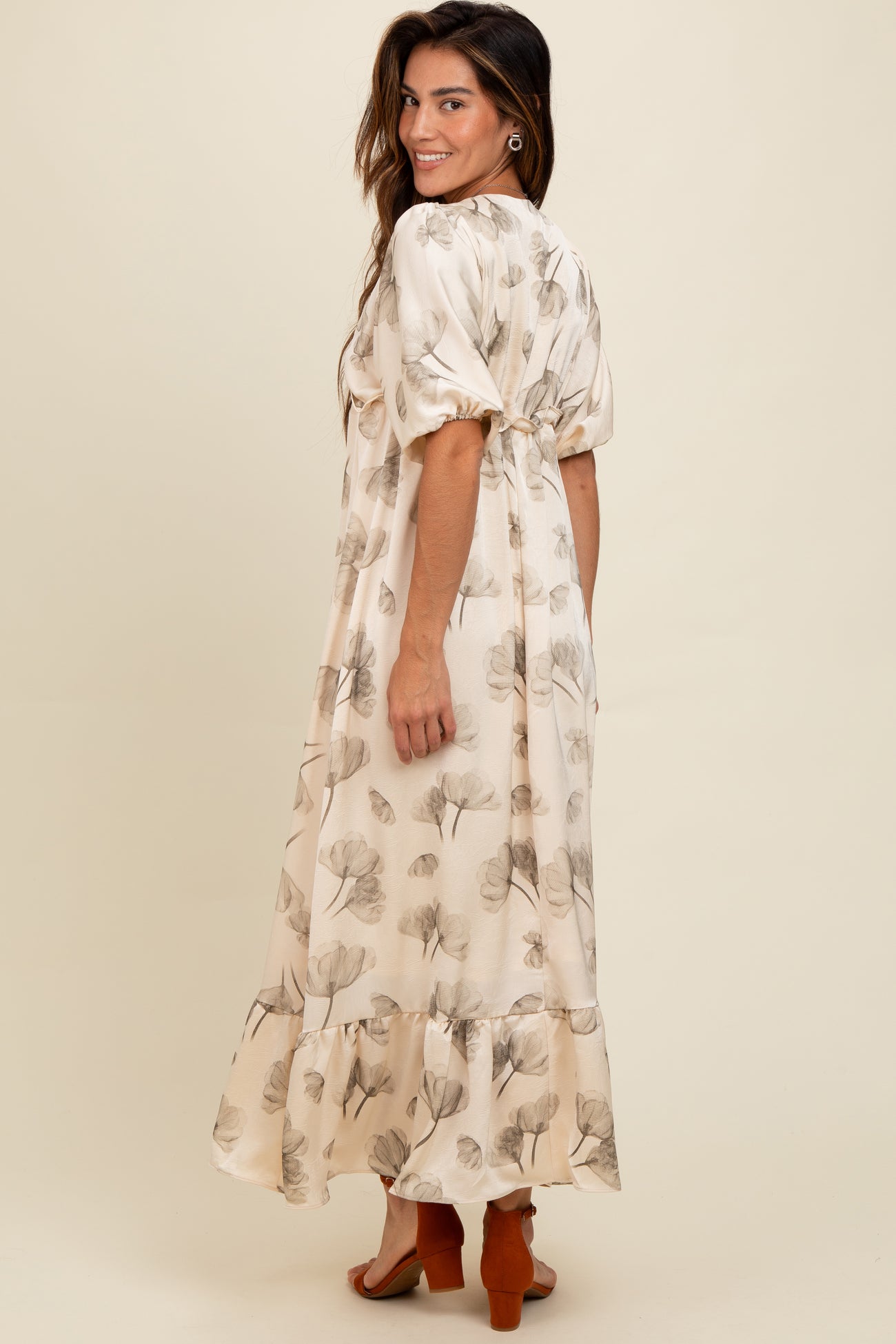 woman wearing a flowy cream maxi dress with floral prints and puff sleeves, styled with heeled sandals