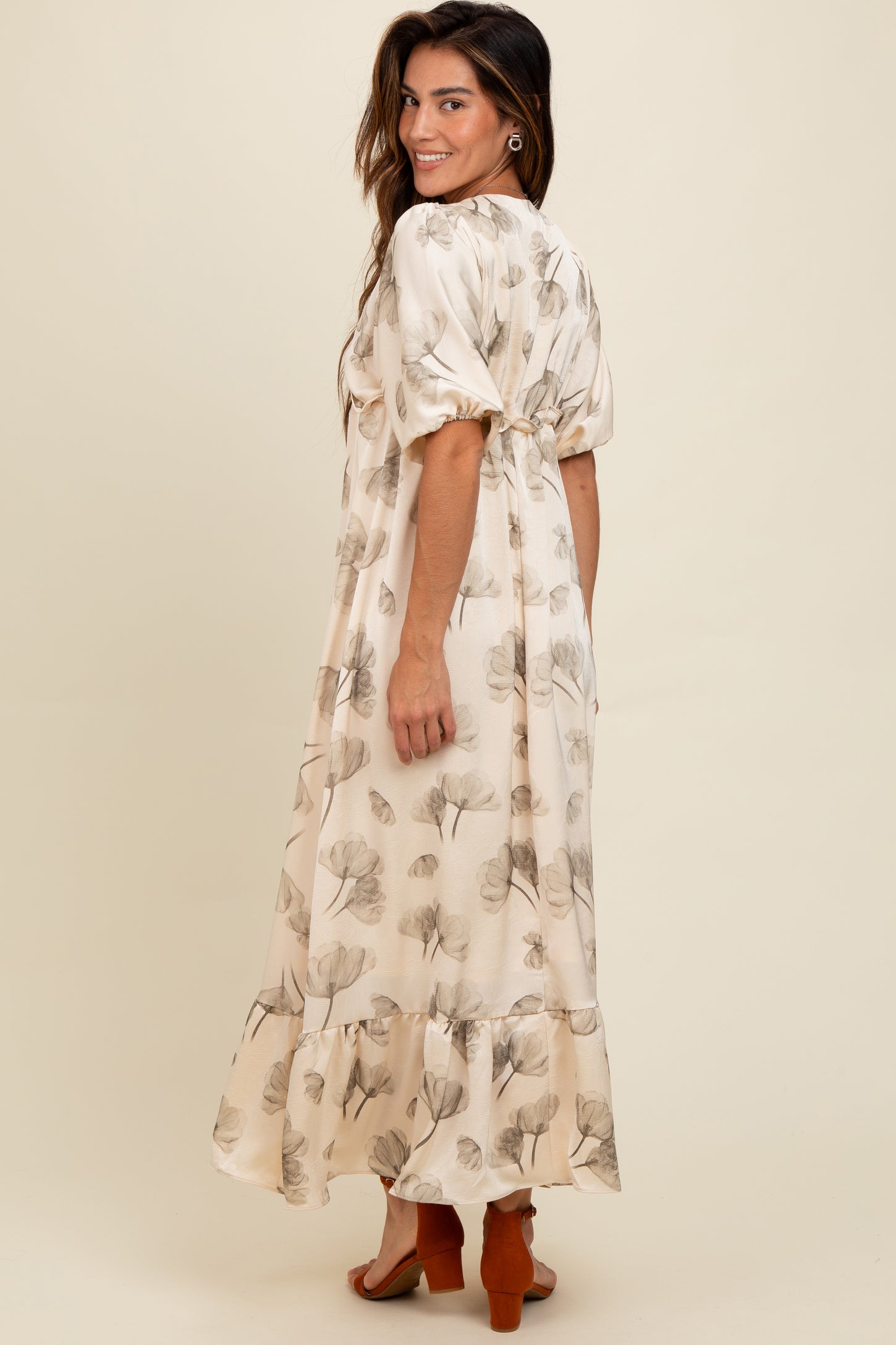 woman wearing a flowy cream maxi dress with floral prints and puff sleeves, styled with heeled sandals