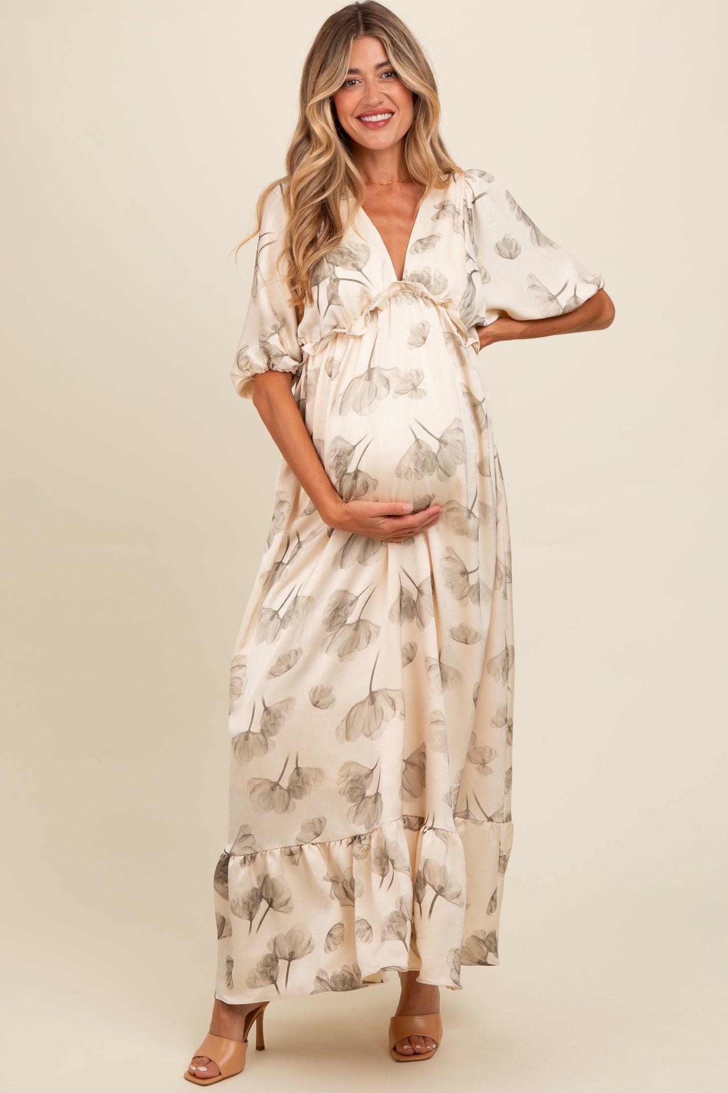 woman wearing a flowy cream maternity maxi dress with leaf patterns and a visible baby bump