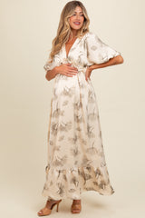 woman wearing a floral print maxi maternity dress, holding her baby bump with a smile