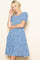 woman wearing a blue floral print short sleeve dress with a tiered skirt and puff sleeves