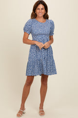 woman wearing a blue floral short puff sleeve dress with a fitted bodice and tiered skirt