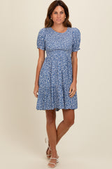 woman wearing a blue floral short sleeve dress with a fitted bodice and tiered skirt