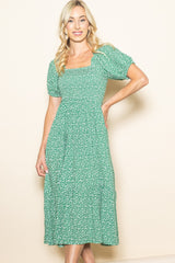 woman wearing a green floral print midi dress with puff sleeves and a square neckline