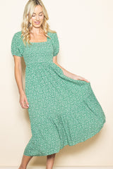 woman wearing a green floral midi dress with puff sleeves and a square neckline, twirling gently