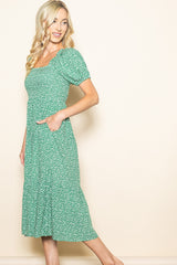 woman wearing a green floral midi dress with puff sleeves and pockets