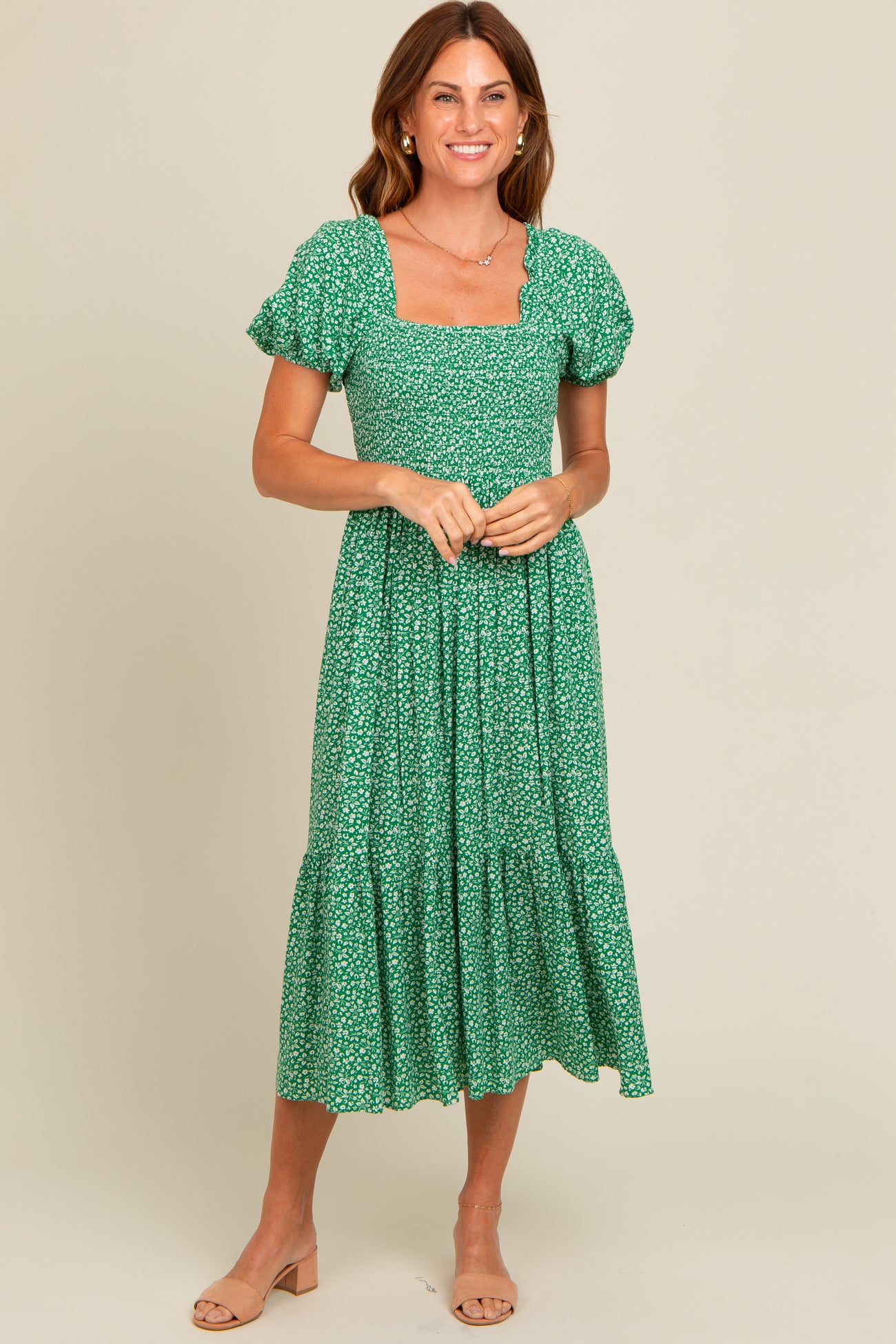 woman wearing a green floral print midi dress with puff sleeves and a square neckline, standing against a neutral background