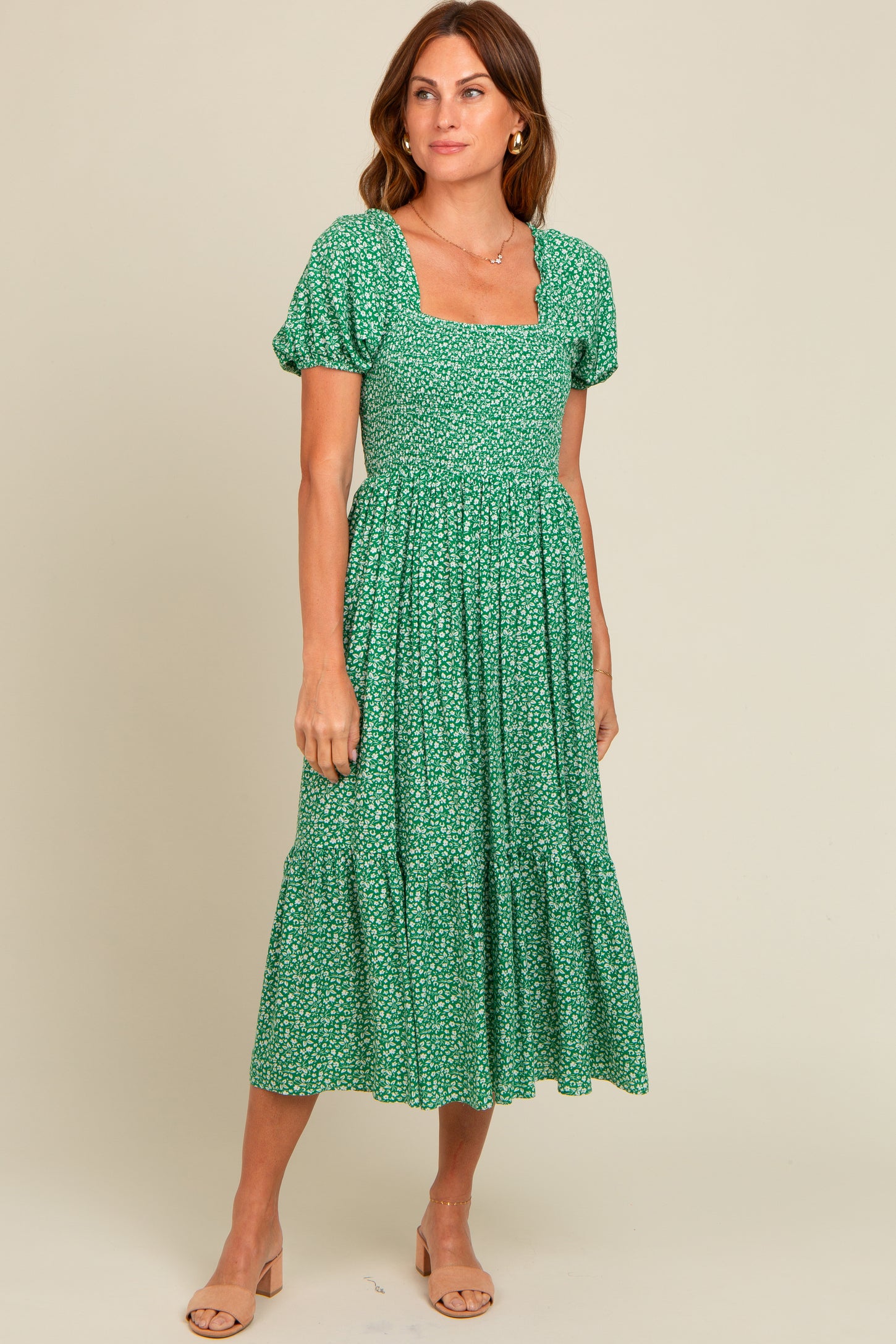 woman wearing a green floral midi dress with puff sleeves and a square neckline, standing against a light background