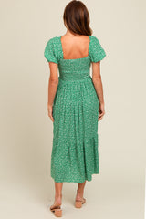 woman wearing a green floral midi dress with puff sleeves and a smocked back detail
