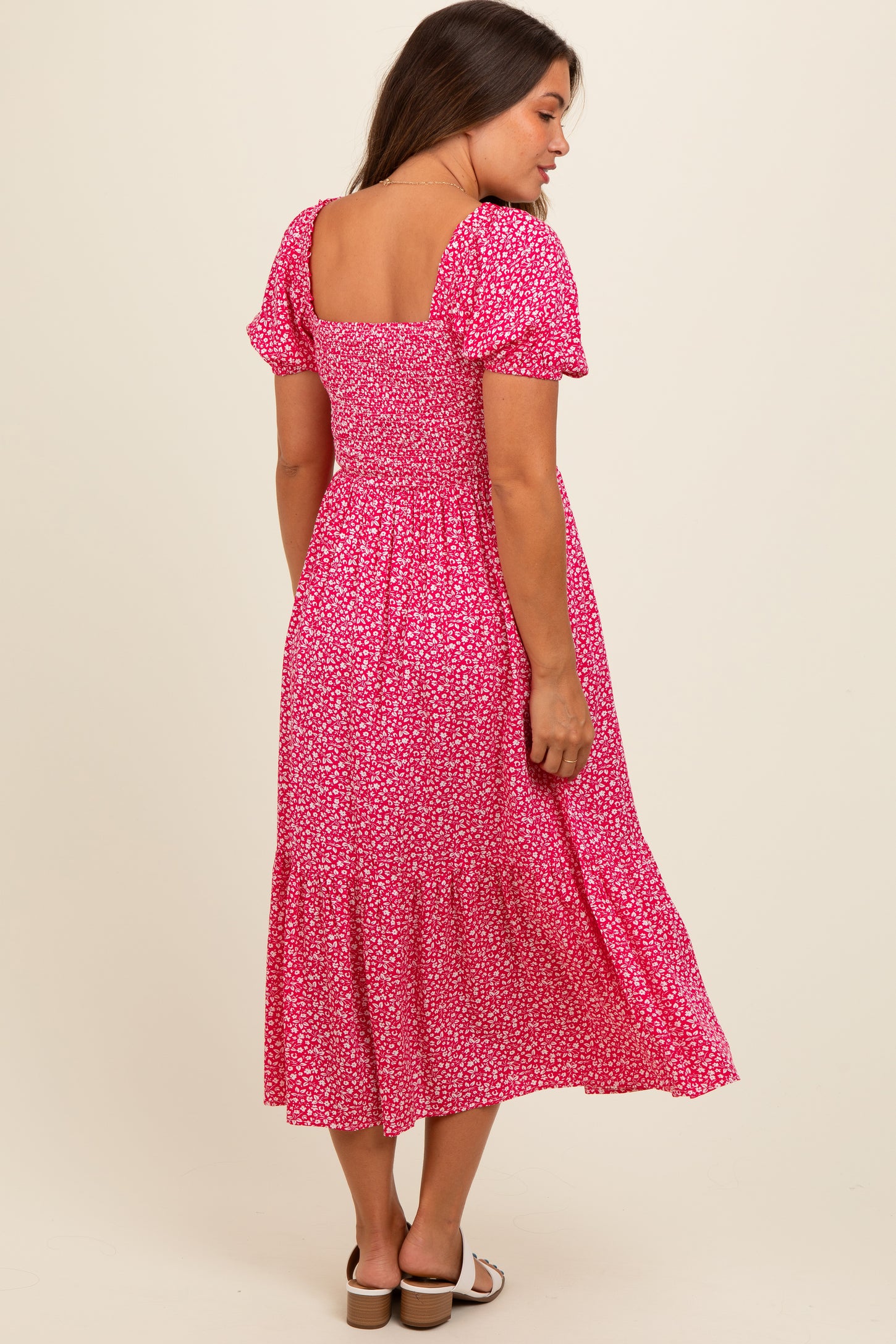 woman wearing a pink floral maternity dress with short puff sleeves and a tiered skirt, showing her baby bump