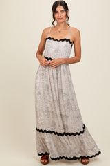 woman wearing a long floral maxi dress with black scalloped trim and spaghetti straps
