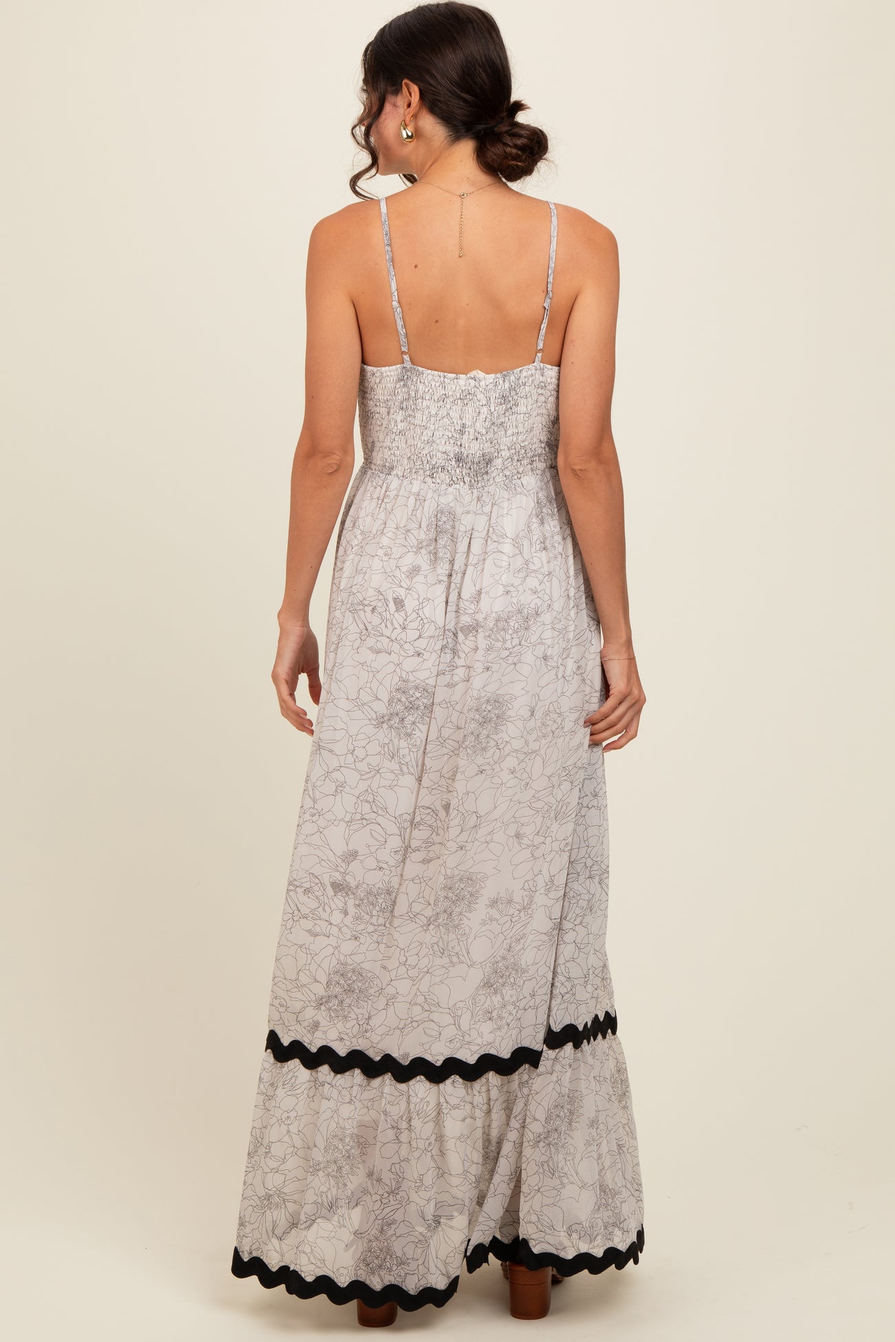 woman wearing a floral print maxi dress with a smocked back and black trim along the hem