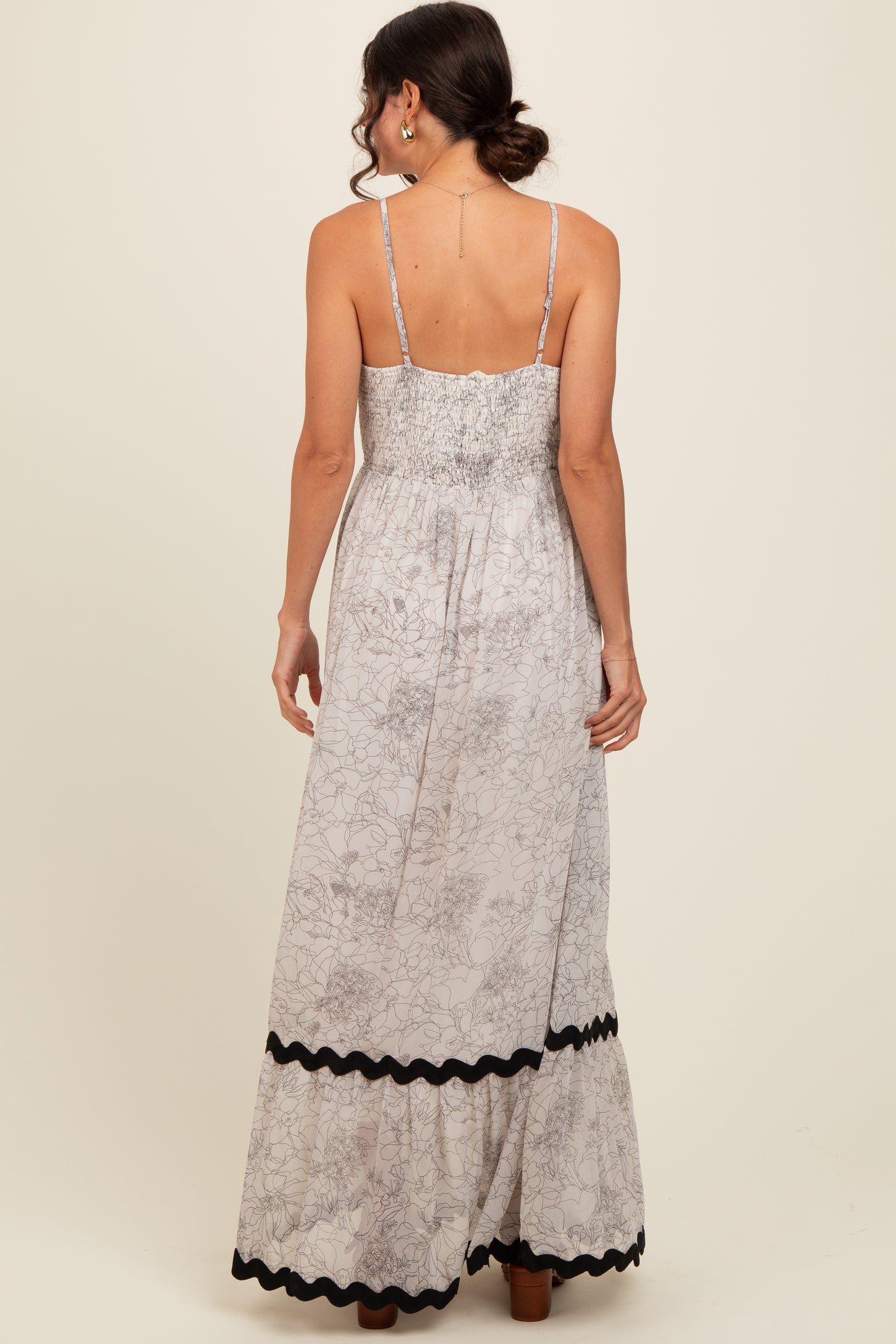 woman wearing a floral print maxi dress with a smocked back and black trim along the hem