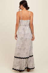 woman wearing a floral print maxi dress with a smocked back and black trim along the hem