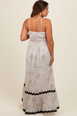 woman wearing a light floral maternity maxi dress with smocked bodice and black ruffle details on the hem