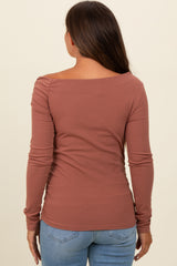 woman wearing a rust-colored long sleeve maternity top with an off-the-shoulder design and slim fit